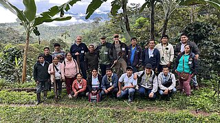 Gruppenfoto von mehreren Personen, die vordere Reihe sitzend, die hintere Reihe stehend, in den grünen Wäldern Perus