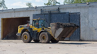 Ein Bagger transportiert Abfälle