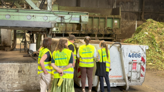 Personengruppe steht vor Bioabfallcontainer