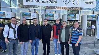 Sieben Personen der ukrainischen Delegation stehen vor dem Eingang der ifat in München